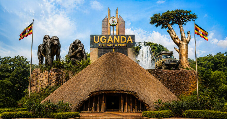 A digital collage celebrating Ugandan heritage under a blue sky, featuring a traditional thatched-roof building in the foreground, a monument reading "UGANDA HERITAGE & PRIDE," gorilla sculptures, a waterfall, a safari vehicle, a baobab tree, and two Ugandan flags.
